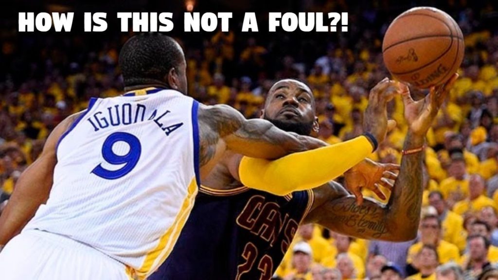 Text: How is this not a foul? Bild på en basketspelare som tydligt slår en annan över armarna på ett otillåtet sätt.