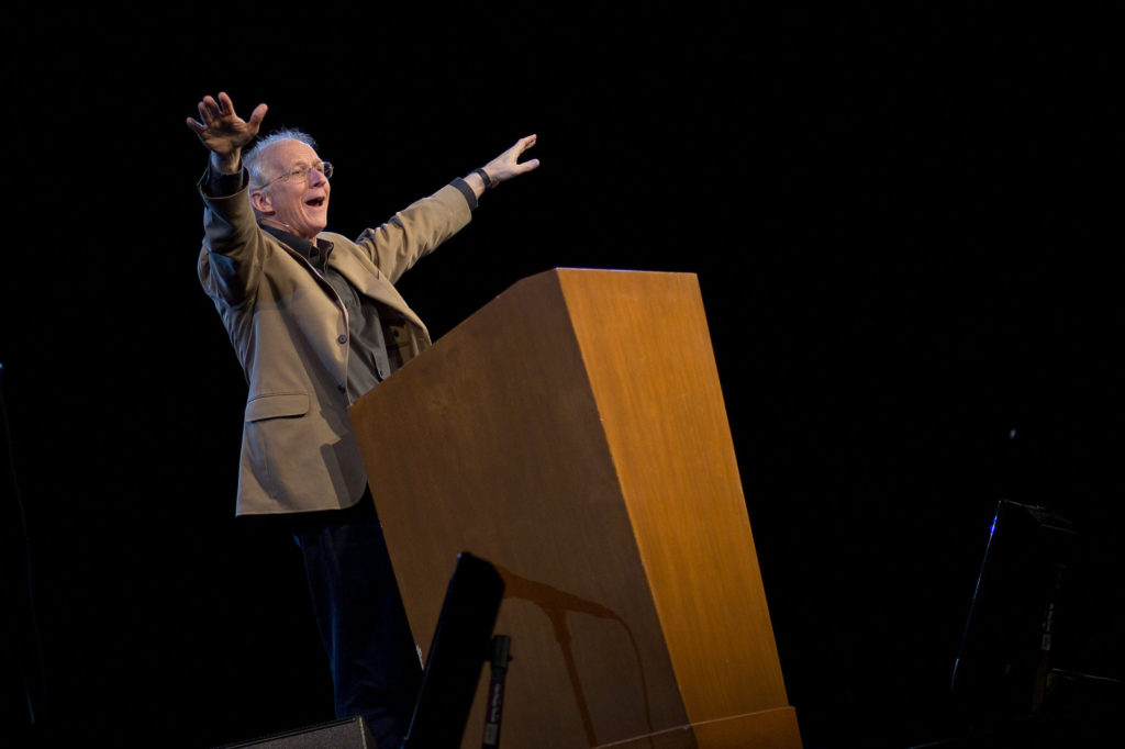 Predikanten John Piper med utsträckta armar som visar entusiasm över budskapet
