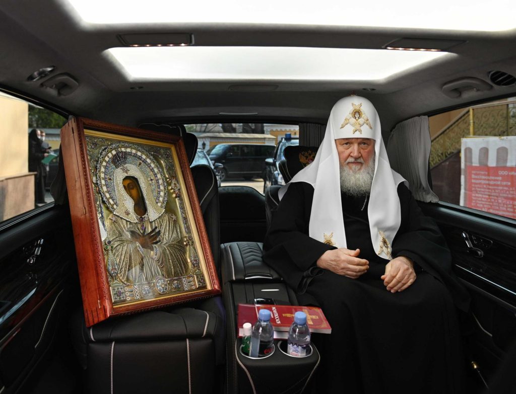 Kirill sitter i sin lyxutrustade Mercedes med en stor ikon bredvid sig.