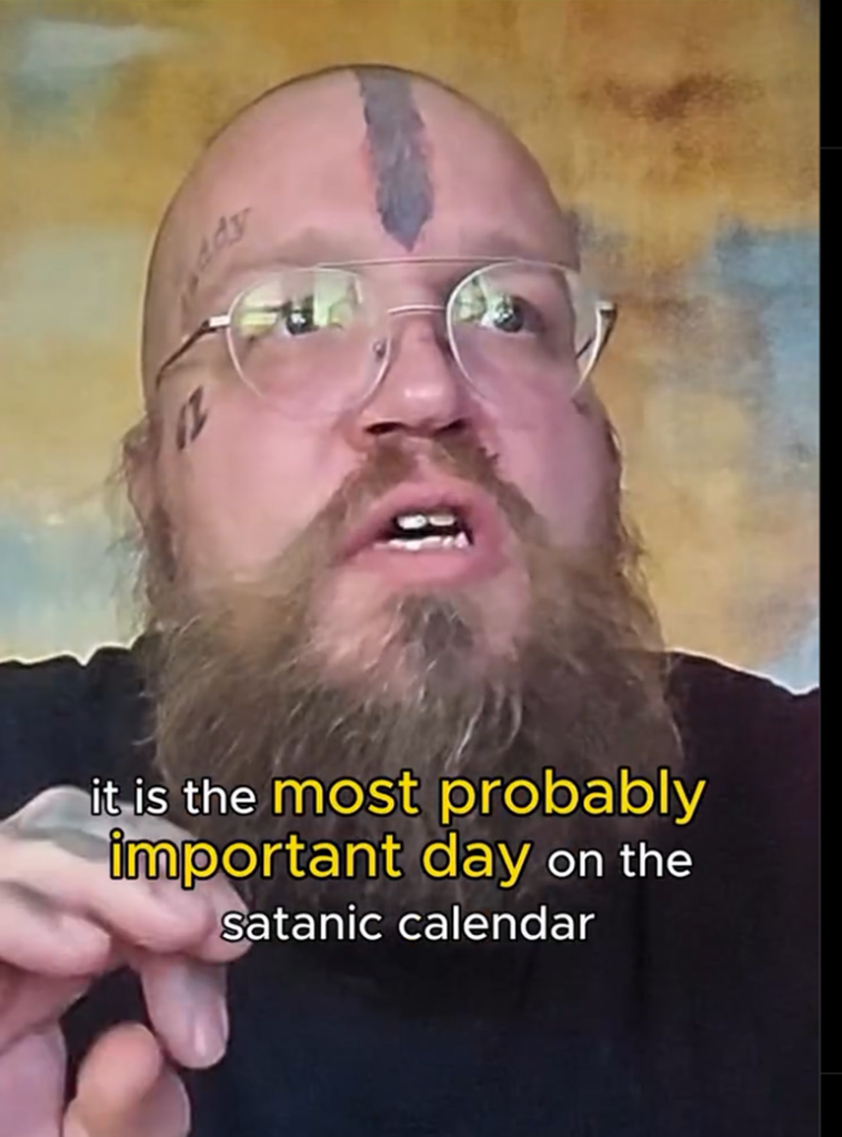 En man med rakat huvud som har en tatuering som går ner i pannan och fler tatueringar på sidan av huvudet och kinderna. Text som säger att det är troligen den viktigaste dagen i den sataniska kalendern.